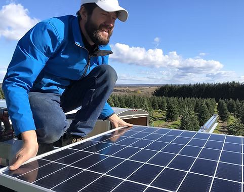 Rudi Fowler installing a solar panel on a rooftop in New Brunswick